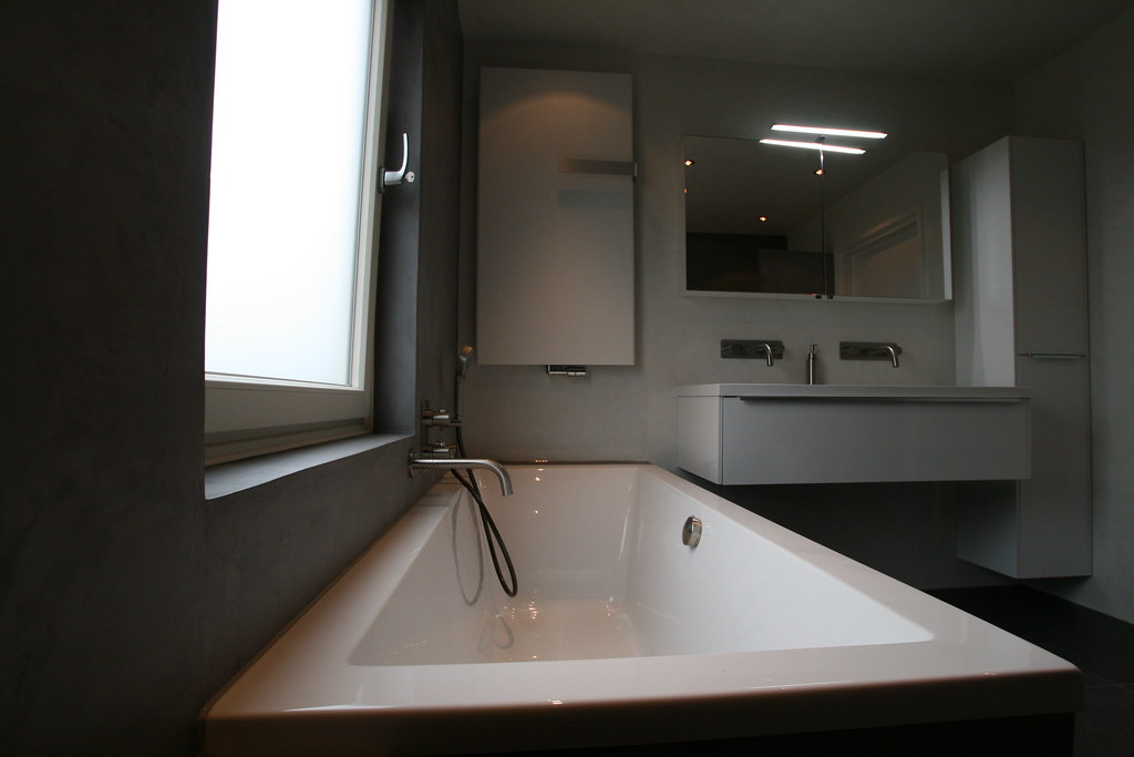 Afgewerkte badkamer met ligbad en badmeubel in betonlook