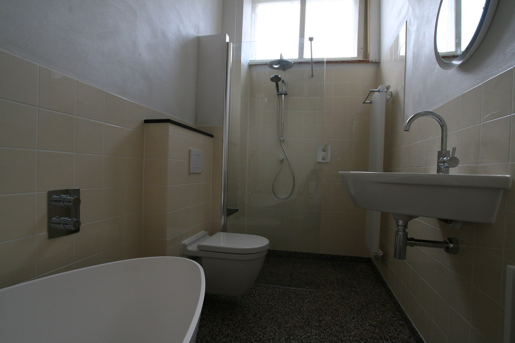 Badkamer met crème tegels, vrijstaand bad en wastafel