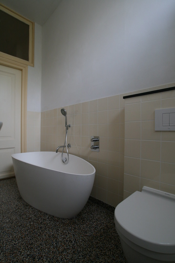 Vrijstaand bad en hangtoilet op een terrazzo vloer