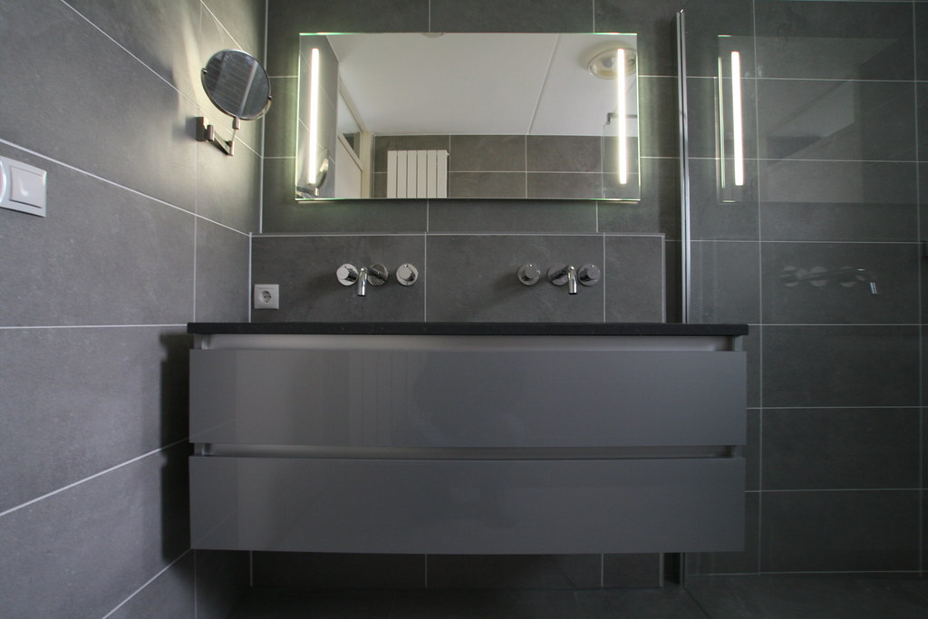 Grijze badkamer met verlichte spiegel en dubbel meubel