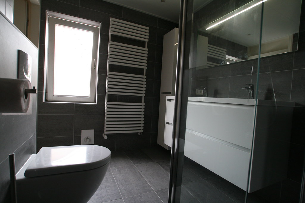 Hangtoilet en glazen douchewand in een grijze badkamer